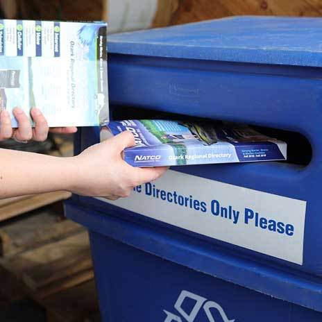 Person placing old phone books into recycling bin